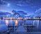 Fishing boats near pier on the sea and snowy mountains at night