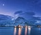 Fishing boats near pier on the sea and snowy mountains at night