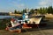 Fishing boats in a pier with sunset light. Small coastal village port. Rocks, promenade with trees, blue sky. Cambados, Spain.