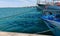 Fishing boats in the port at the dock, reflections of the sun in the green sea and taut hawsers