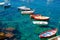 Fishing colorful multicolored boats on transparent clear water with visible bottom in small stone harbor of Riomaggiore village Na