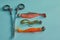 Fishing equipment. Three fishing vibrotails and a pair of scissors to extract the hook on a blue background