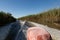 Fishing motorboat sails along channel among the reeds. Trail on water surface