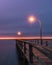 A fishing pier during dusk lit up by lamp posts. Blue hour moody purple sky - Long Island NY