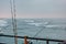 Fishing poles hang over the rail of a pier and over the water.