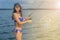 Fishing. Portrait of sexy fisher girl in swimsuit with tackles at lake. Warm light toned background