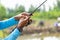 Fishing reel and rod in fisherman hand in a pond