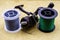 Fishing reel and spools of cords on the background of tarpaulin. Green and gray fishing line. Spools of braided fishing line