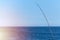 Fishing rod against blue ocean or sea background, copy space, Waiting for biggest haul, Meditative relax sport
