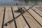 Fishing rod or angler lying on wood coast over river or lake in summer close up