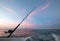 Fishing rod on charter fishing boat against pink sunrise sky on the Sea of Cortes in Baja Mexico