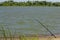 Fishing rod on the sandy shore of the rustic river at noon. Fishing and tourism as one of the types of recreation on weekends