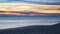 Fishing rods on Faro beach at sunset in Algarve, Portugal as waves break