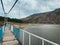 Fishing rods and fishermen standing on steel cable suspension bridge over big lake