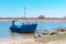 A fishing vessel on the shore, small blue fishing schooner