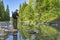 Fishing at wild mountain river. Fisherman catch trout fish at stone coast of forest stream