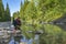 Fishing at wild mountain river. Fisherman catch trout fish at stone coast of forest stream