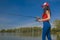 Fishing. Young sexy woman catches fish by spinning rod at lake in summer