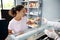 Fishmonger serving customer of fish store. Mixed race woman, purchaser tasting caviar at seafood shop. Seafood retail. Consumerism