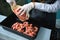 The fishmonger stands behind the counter in a work apron and puts fresh frozen chilled red shrimp on a tray. Mediterranean fish