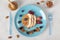 Fishs-shaped pancake with peaches, berries, granola and almonds on blue plate, breakfast idea for kids