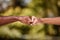 Fist bump of two interracial men outdoor against a blur background. Closeup of diverse athletes doing social gesture