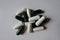 Fistful of white capsules of magnesium citrate and green capsules of multivatamins