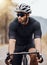 Fit and active indian man wearing a helmet and sunglasses to cycle outdoors for a workout. Focused mixed race athlete