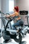 Fit active woman in the gym using gym machines, working out on bicycle.  Fitness and bodybuilding concept