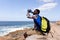 Fit afrcan american man wearing backpack resting drinking water on the coast