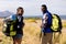 Fit african american couple wearing backpacks nordic walking on coast