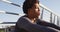 Fit african american man exercising outdoors in city, resting sitting on footbridge