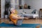 Fit aged woman doing abs exercises, sitting in boat yoga pose at home, doing domestic training on fitness mat