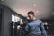 A fit asian man in a sweatshirt does alternating seated dumbbell curls. Working out and training biceps. Open air gym setting