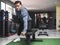 A fit asian man in a sweatshirt does one arm dumbbell rows. Back workout exercise. Inside a gym