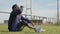 Fit athlete with prosthetic leg sitting on grass, drinking water