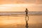 Fit and athletic Asian Chinese sporty woman running on beautiful beach doing jogging workout on sunset in fitness healthy lifestyl