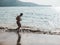 A fit and athletic male does a light jog barefoot along the beach. Recreational and low intensity cardio at a scenic coastline