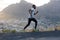Fit athletic male jogger runs fast along road, does workout outdoor, amazing mountain landscape in background, breathes