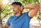 Fit athletic man smiling while stretching his arms during a workout at the park. Hispanic man doing warm-up exercises