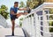 Fit athletic mixed race man stretching on a bridge in the city during his workout. Young hispanic man doing warm up