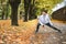 Fit athletic woman doing workout before jogging in the autumnal city park on the kids playground. Young fitness female runner