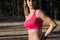 Fit athletic woman standing in a forest, sweating and taking a break from intense workout.