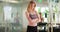 Fit blonde millennial woman in workout gear standing in gym with arms crossed