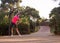 Fit caucasian middle aged woman do warming up on the footpath outdoor in summer among greenery, selective focus.