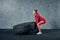 Fit female athlete working out with a huge tire. Side view. Sportswoman doing an strength exercise training.