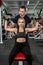 Fit female client working out with personal male instructor with heavy dumbbells at the gym