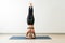 Fit Female Practicing Headstand In Yoga Studio
