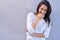 Fit of giggles. Portrait of an attractive young woman standing against a gray background while covering her mouth.