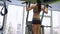 Fit girl looking focused and determined while doing pull-ups in a gym on gymnastic rings